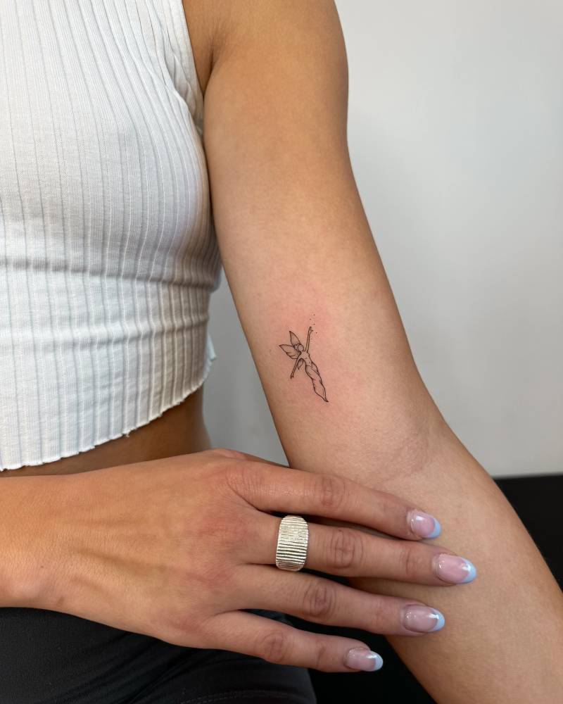 Fine line style fairy tattoo located on the inner arm.